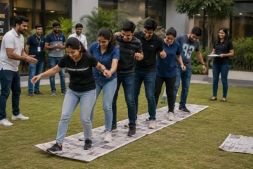 Corporate teams participating in Newspaper Canvas Race, using newspaper sheets to move across a course while demonstrating teamwork, communication, coordination, and problem-solving skills.